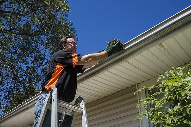 smiling worker fixing gutters on a residential home in Alpha NJ